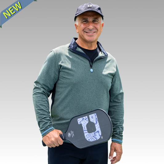 Man holding a pickleball paddle with a gray background