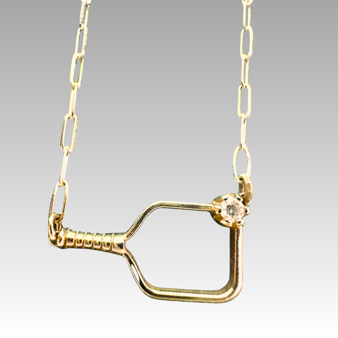 Gold necklace with a unique pendant on a gray background