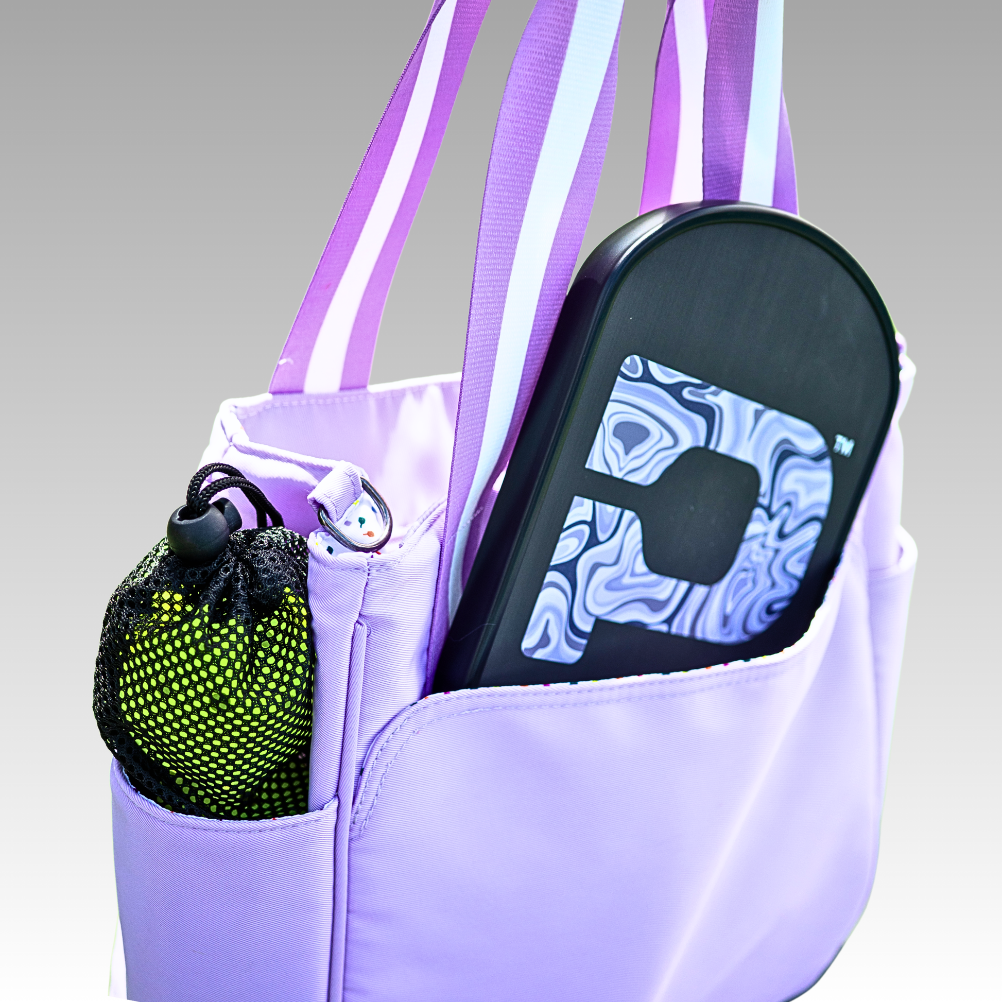 Purple tote bag with a sandal and green mesh bag inside on a gray background