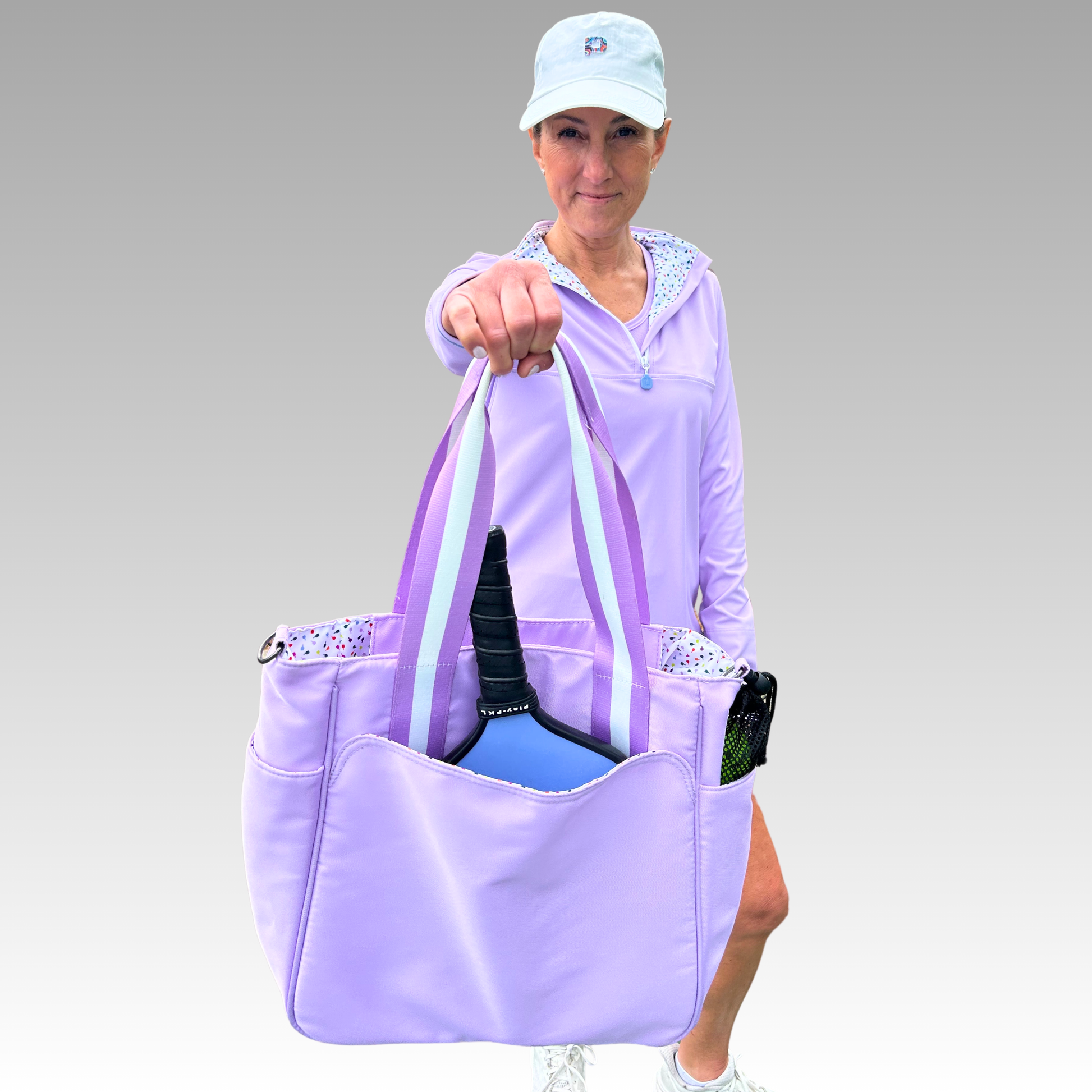 Woman holding a purple tote bag with a paddle, wearing a matching outfit.